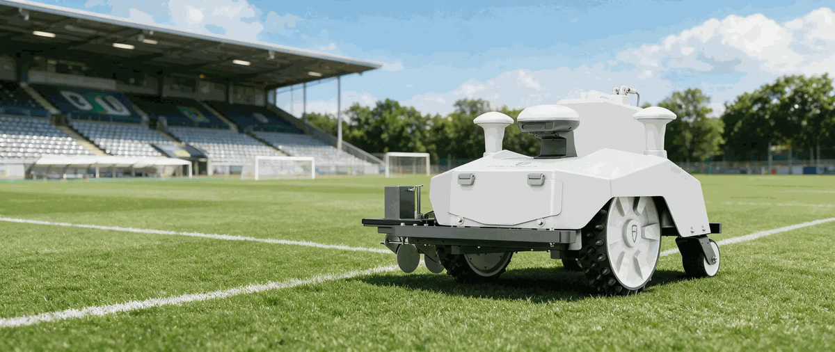 Autonomous line marking robot on a sports field in front of a stadium grandstand