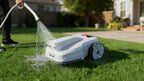 FJD FV2000 robotic lawn mower being rinsed with a garden hose on a lawn