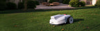 FJD FV2000 robotic lawn mower on a backyard lawn at dusk