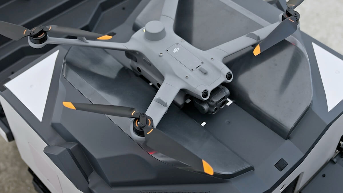 DJI Matrice 3D series drone with orange-tipped propellers resting on a DJI Dock 2 landing pad