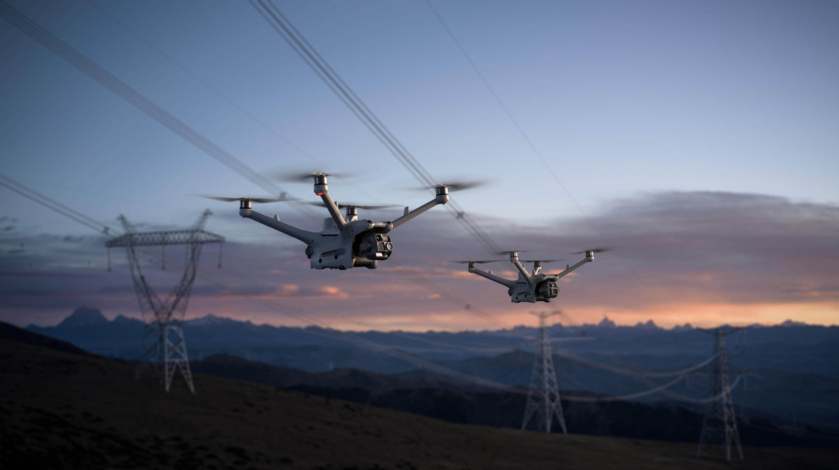 Two DJI Matrice 4D series drones inspecting high-voltage power lines at dusk